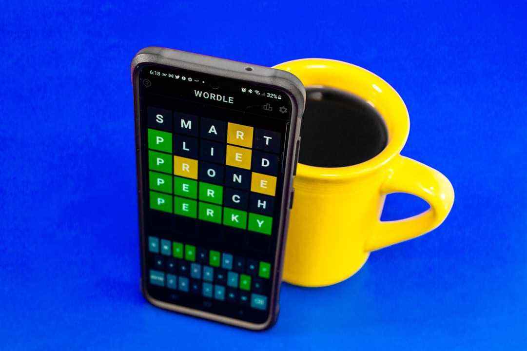 Wordle sur un écran de téléphone, à côté d'une tasse de café