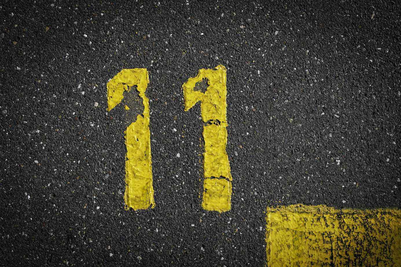 signe sur l'asphalte, numéro onze peint en jaune sur la rue grise, lignes jaunes comme un coin sur la route, espace pour le texte