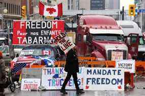 Un manifestant marche devant des camions garés alors que les manifestants continuent de protester contre les mandats de vaccination à Ottawa mardi.