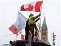 Des gens agitent des drapeaux au sommet d'un camion devant la colline du Parlement alors que les camionneurs et leurs partisans continuent de protester contre les mandats de vaccination contre la COVID-19 à Ottawa, Ontario, Canada, le 6 février 2022.  
