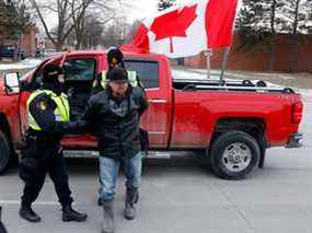 La police arrête un manifestant alors qu'il élimine les manifestants contre les mandats de vaccination contre le COVID-19 qui ont bloqué l'entrée du pont Ambassador à Windsor, Ontario, Canada, le 13 février 2022. (Photo de JEFF KOWALSKY / AFP)