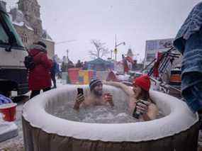 Les manifestants Gabriel (L) et Jean-Philippe (R) sont assis dans un bain à remous entre des camions lors d'une manifestation contre les règles sanitaires en cas de pandémie et le gouvernement Trudeau, devant le Parlement à Ottawa, Ontario, le 12 février 2022. (Photo d'Ed JONES /AFP)
