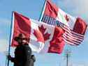 Un manifestant porte des drapeaux canadiens et américains tout en bloquant l'entrée du pont Ambassador à Windsor, en Ontario, le 12 février 2022.