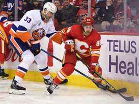 L'attaquant des Flames de Calgary Andrew Mangiapane se bat pour la rondelle contre le défenseur des Islanders de New York Zdeno Chara au Scotiabank Saddledome de Calgary le samedi 13 février 2022.