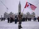 Un manifestant tient un drapeau américain et canadien lors d'une manifestation de camionneurs contre les mandats de la COVID-19, devant le Parlement du Canada à Ottawa le 12 février 2022.