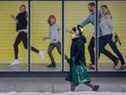 Un piéton portant un masque passe devant une peinture murale d'une famille profitant d'une promenade tranquille sans masse à Toronto pendant la pandémie de COVID-19, le jeudi 3 février 2022.