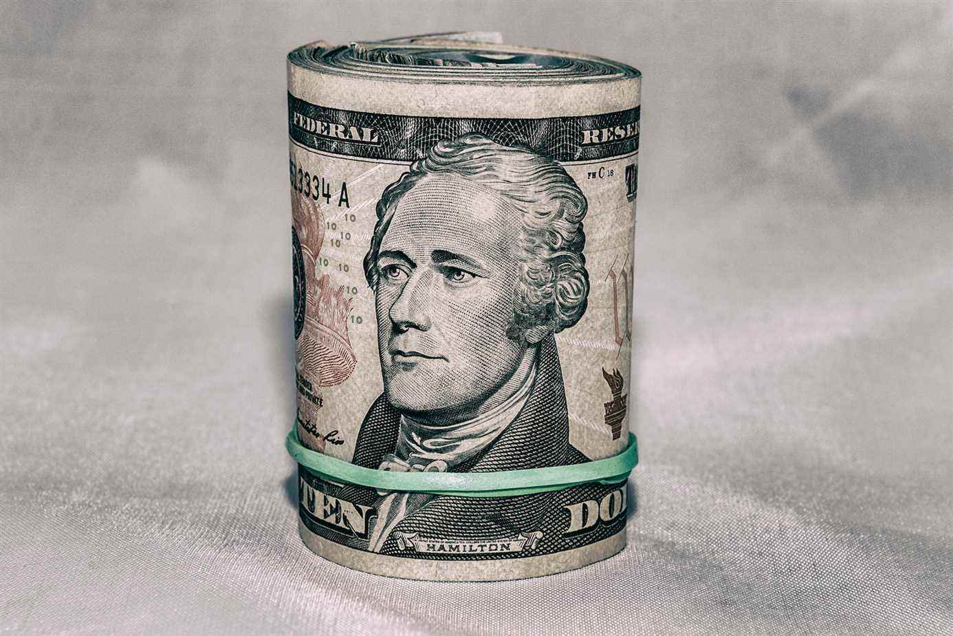 Un rouleau de monnaie américaine avec un billet de 10 $ à l'extérieur, le portrait d'Alexander Hamilton au centre.