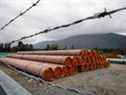 Des morceaux du projet Trans Mountain Pipeline se trouvent dans un lot de stockage à l'extérieur de Hope, en Colombie-Britannique, en juin dernier.  Les conditions météorologiques volatiles et la pandémie ont ralenti la construction.