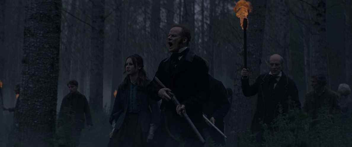 Alistair Petrie et un groupe d'autres hommes armés de fusils chassent un monstre à travers les bois sombres dans The Cursed