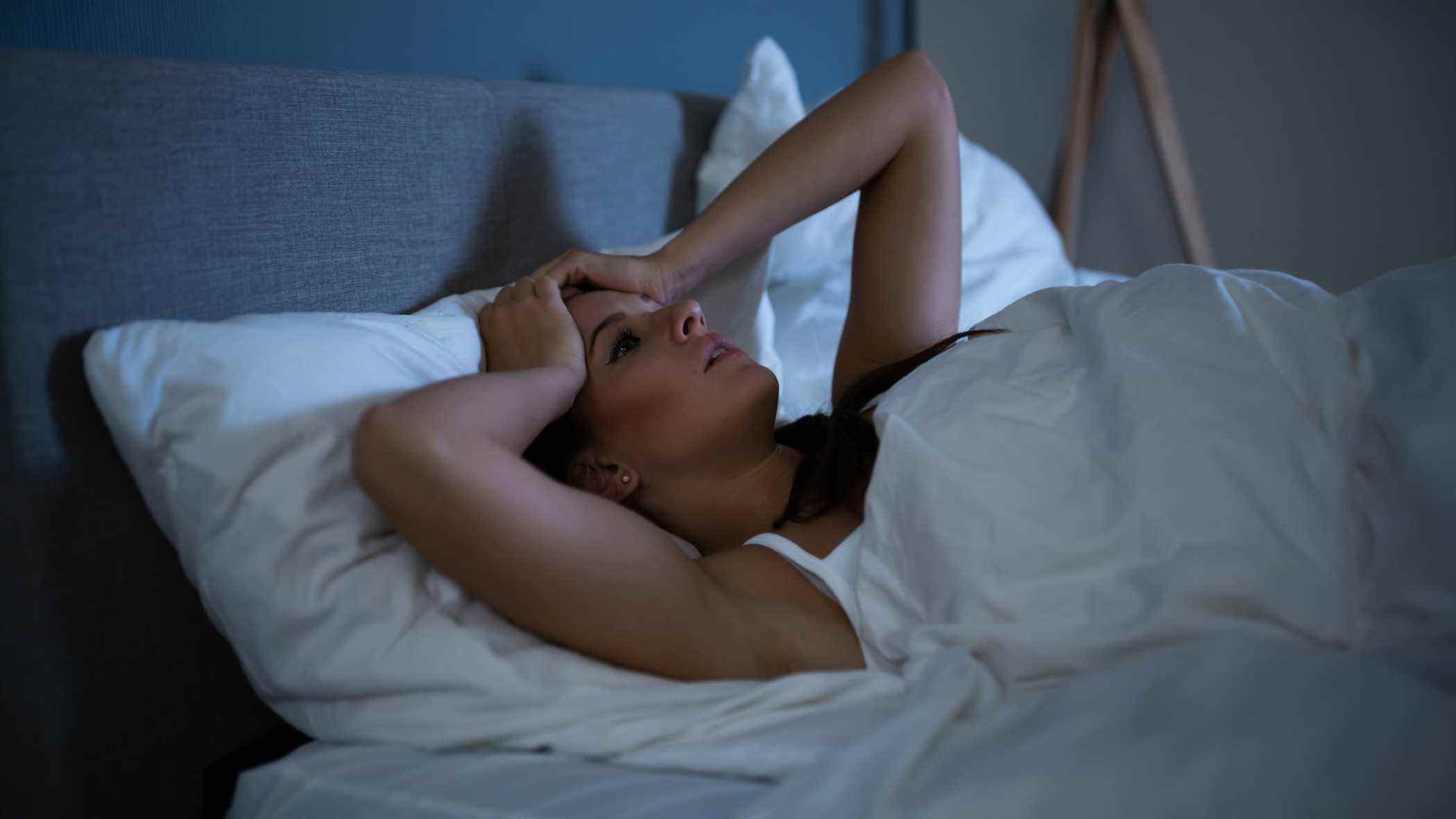 Une femme reste éveillée dans son lit la nuit parce qu'elle est trop mal à l'aise pour dormir