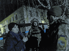 Des soldats ukrainiens discutent avec un résident local devant un jardin d'enfants qui, selon des responsables militaires, a été endommagé par des bombardements, à Stanytsia Luhanska, Ukraine, le 17 février 2022.