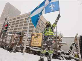 Un manifestant agite un drapeau du Québec devant l'Assemblée nationale à Québec le samedi 19 février 2022.