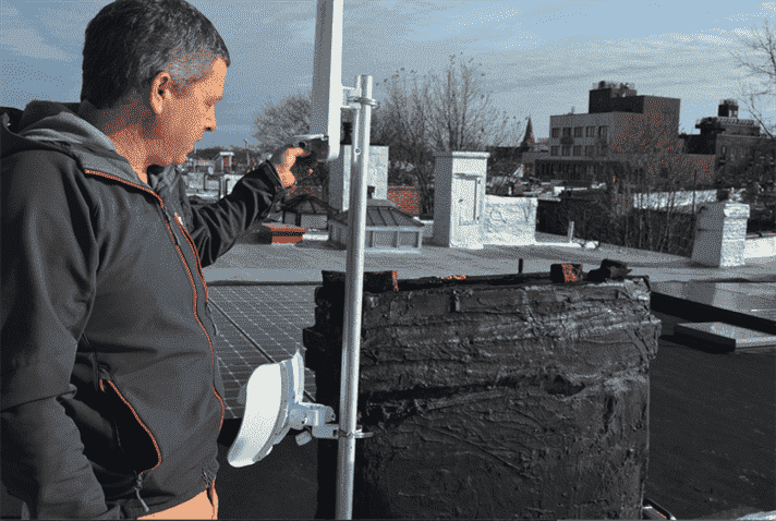 Un bénévole du NYC Mesh installe du matériel de réseautage sur un toit.