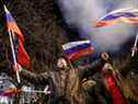 Des militants pro-russes célèbrent dans une rue alors que des feux d'artifice explosent dans le ciel, après que le président russe Vladimir Poutine a signé lundi un décret reconnaissant deux régions séparatistes soutenues par la Russie dans l'est de l'Ukraine en tant qu'entités indépendantes.