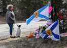 Denise Caume et son chien, Mimi, sont vus devant le mémorial de fortune, réalisé à la mémoire d'une fusillade de masse à Portapique, en Nouvelle-Écosse, le 23 avril 2020.
