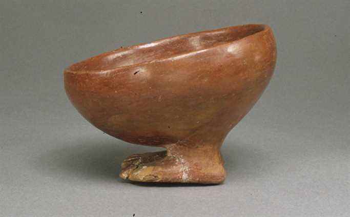 Un petit bol arrondi brun orange reposant sur des pieds en forme d'homme, de l'Egypte prédynastique vers 3900 -3650 av.