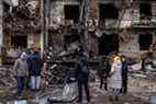 Les gens regardent l'extérieur d'un bloc résidentiel endommagé touché par une frappe de missile tôt le matin le 25 février 2022 à Kiev, en Ukraine.  