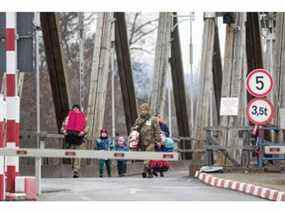 Des soldats ukrainiens aident une femme et des enfants à traverser la frontière au poste de douane de Sighetu Marmatiei, à Baia Mare, en Roumanie, le 26 février 2022.