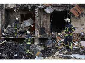 Des pompiers éteignent un incendie à l'intérieur d'un immeuble résidentiel endommagé par un missile le 25 février 2022 à Kiev.