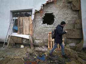 Un habitant du village de Stanytsia Luhanska, sous contrôle ukrainien, marche parmi les décombres après le bombardement par des séparatistes soutenus par la Russie le 18 février 2022.