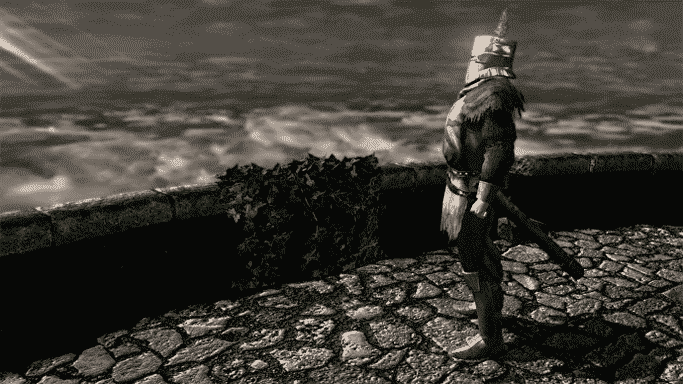 Solaire, l'étrange chevalier adorateur du soleil dans Dark Souls, se tient face à l'objet de son affection au bord d'une zone pavée de pierre ouverte sur le ciel
