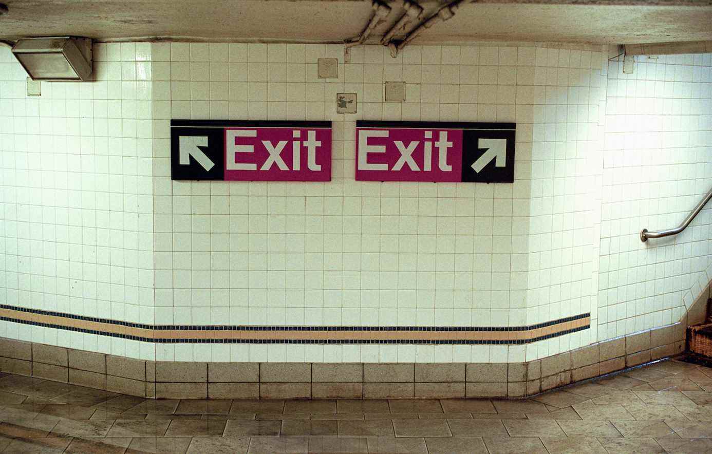 Deux panneaux de sortie de métro pointant dans des directions opposées