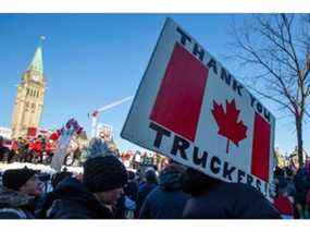 Des partisans du Freedom Convoy se tiennent devant les édifices du Parlement alors que des camionneurs participent à un convoi pour protester contre les mandats de vaccination contre la COVID-19 pour les camionneurs transfrontaliers à Ottawa, le 29 janvier 2022.