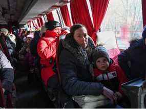 Des personnes, qui ont été évacuées des régions contrôlées par les séparatistes dans l'est de l'Ukraine, sont assises dans un bus alors qu'elles arrivent à une gare pour quitter la ville de Taganrog dans la région de Rostov, en Russie, le 20 février 2022.