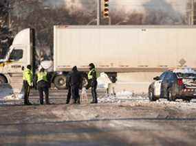 Des policiers montent la garde à une barricade le long de la route menant au passage frontalier du pont Ambassador à Windsor, en Ontario, le lundi 14 février 2022.