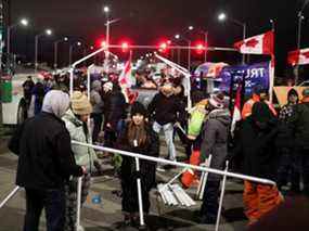Les gens érigent une tente alors que les chauffeurs de camion et les partisans continuent de bloquer l'accès au pont Ambassador, qui relie Detroit et Windsor, pour protester contre les mandats de vaccination contre la COVID-19, à Windsor, en Ontario, le 10 février 2022.