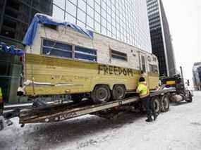 Un homme sécurise une caravane avant qu'elle ne soit transportée à Ottawa, le dimanche 20 février 2022.