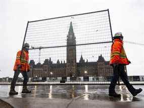 Les équipes transportent un morceau de clôture pour étayer les portes existantes le long de la rue Wellington sur la Colline du Parlement, jeudi.