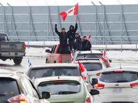 Jeudi, des personnes brandissant des drapeaux canadiens manifestent à l'aéroport international d'Ottawa.