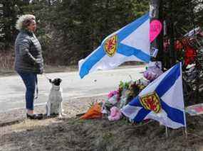 Denise Caume et son chien, Mimi, sont vus devant le mémorial de fortune, réalisé à la mémoire d'une fusillade de masse à Portapique, en Nouvelle-Écosse, le 23 avril 2020.