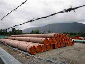 Des morceaux du projet Trans Mountain Pipeline se trouvent dans un lot de stockage à l'extérieur de Hope, en Colombie-Britannique, en juin dernier.  Les conditions météorologiques volatiles et la pandémie ont ralenti la construction.