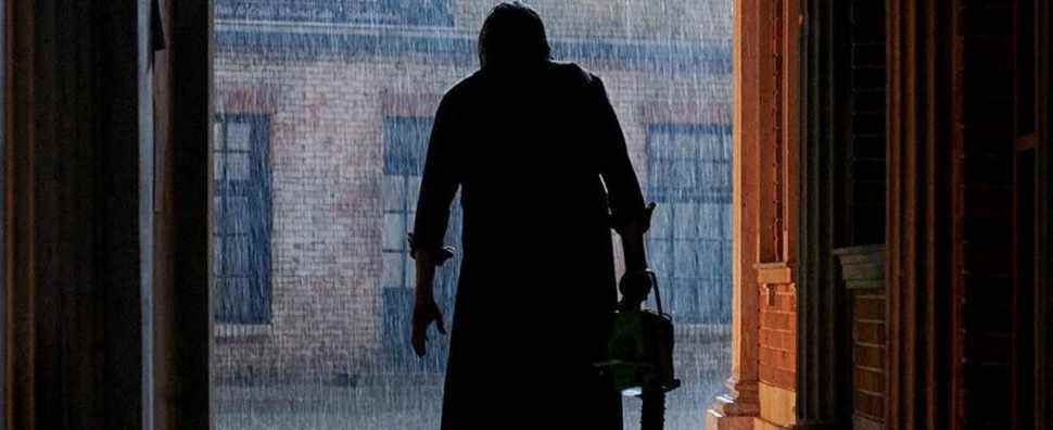 Leatherface's silhouette holding a chainsaw in the rain