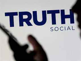 Le logo du réseau social Truth est affiché derrière une femme tenant un smartphone sur cette illustration prise le 21 février 2022.