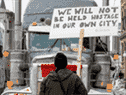 Un homme à Ottawa tient une pancarte invitant les participants au Freedom Convoy à rentrer chez eux, le 2 février 2022. Les camionneurs disent qu'ils n'ont pas l'intention de partir.