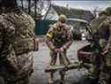 Des soldats ukrainiens déchargent des armes du coffre d'une vieille voiture, au nord-est de Kiev, le 3 mars 2022. 