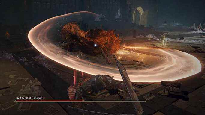 Le loup rouge de Radagon, un boss d'Elden Ring, balance une épée flamboyante en arc de cercle vers le joueur.