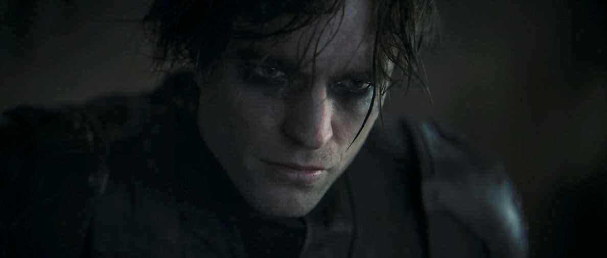 Robert Pattinson dans le rôle de Bruce Wayne dans The Batman.  Il porte son costume de Batman mais sans le masque ;  ses yeux cernés de maquillage noir.
