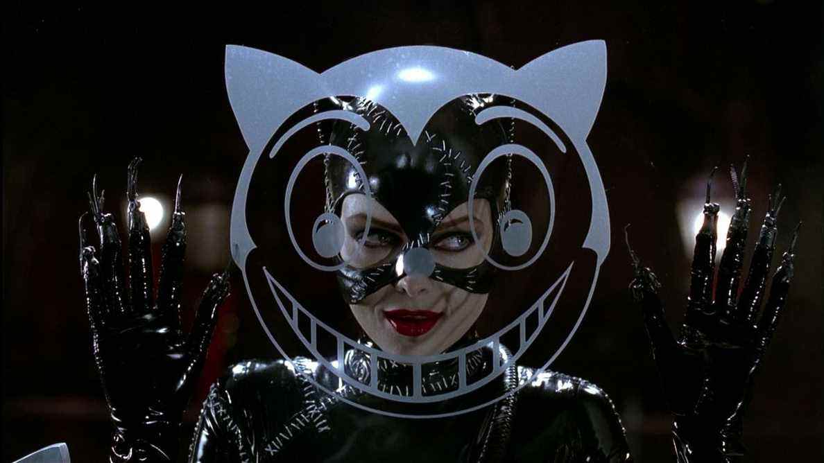 Michelle Pfeiffer dans le rôle de Catwoman dans Batman Returns, debout derrière une image de tête de chat peinte sur du verre