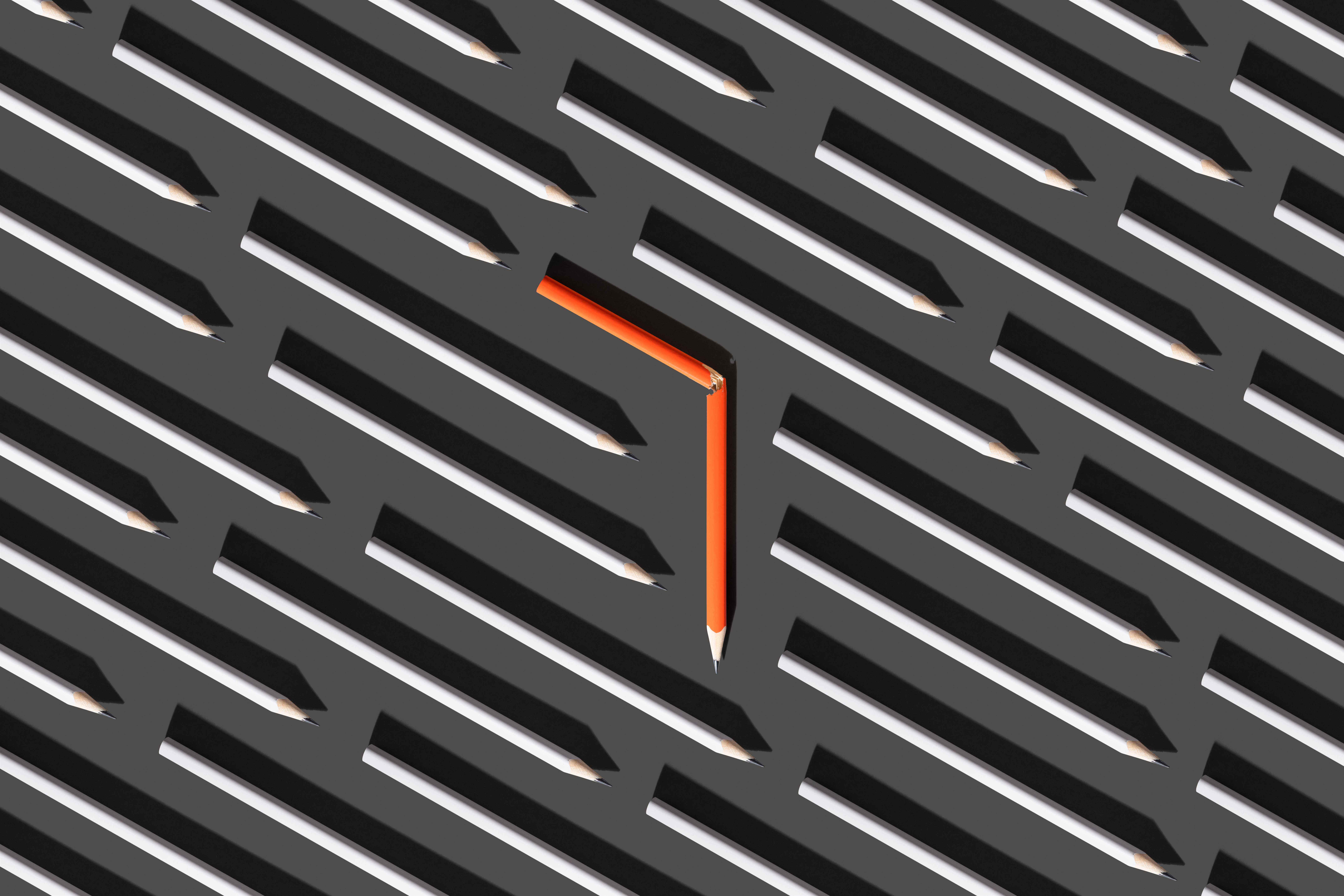 Image d'un crayon cassé orange au milieu de crayons gris droits pour représenter le pivotement.