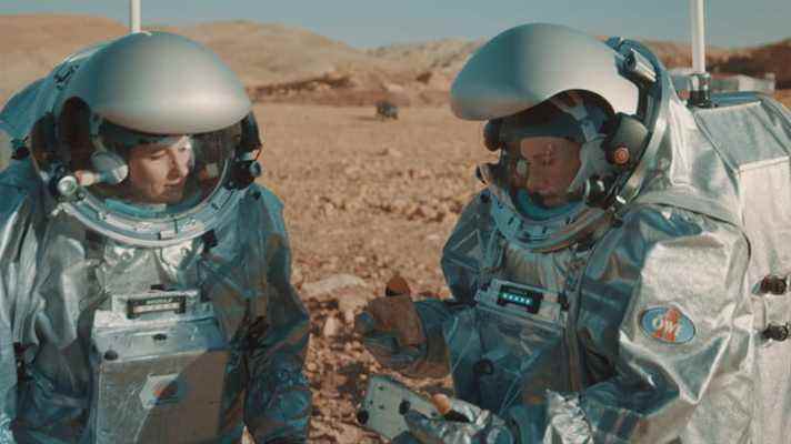 Une paire de scientifiques en combinaison d'astronaute simule l'exploration de Mars dans le désert.