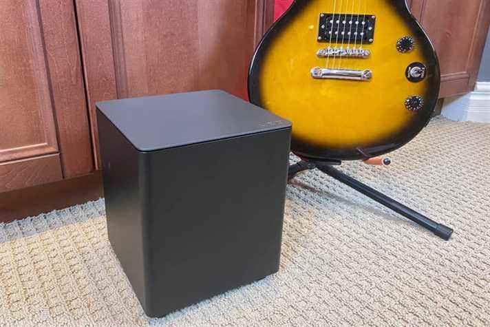 Le caisson de basses sans fil de la barre de son Vizio M-Series 2.1 à côté d'une guitare.