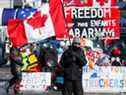 Une personne agite un drapeau canadien devant des banderoles en soutien aux camionneurs à Ottawa, le 14 février 2022.