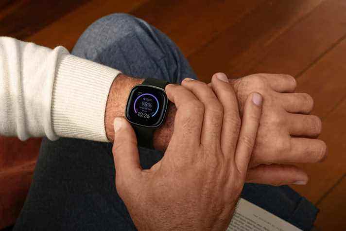 Un Fitbit Sense de couleur carbone est porté au poignet d'un homme.