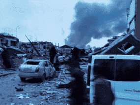 De la fumée monte au milieu de bâtiments et de véhicules endommagés à la suite d'une frappe aérienne des forces russes sur la base militaire de Yavoriv à Yavoriv, ​​en Ukraine, le 13 mars 2022.