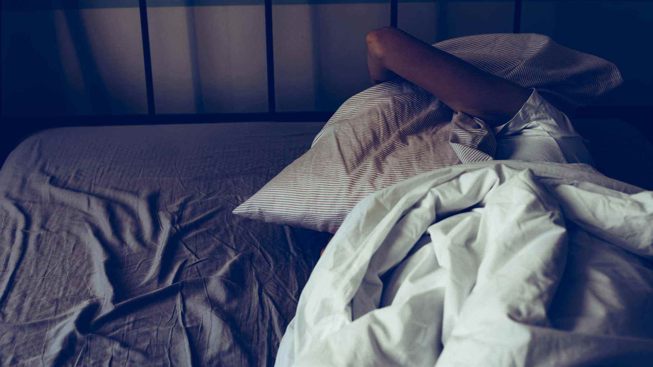 Une femme est allongée dans son lit, incapable de bien dormir