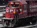 Un employé du Chemin de fer Canadien Pacifique marche le long d'une locomotive dans une gare de triage à Calgary.